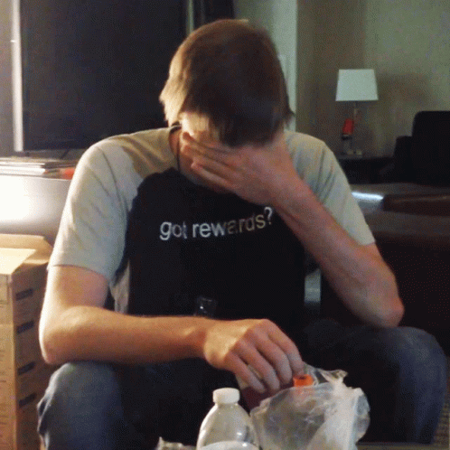 A Man Wearing A Shirt That Says Got Rewards Covers His Face GIF