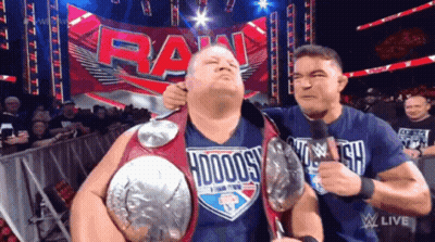 A Man Wearing A Shirt That Says ' Hodogs ' On It Is Being Held By Another Man GIF
