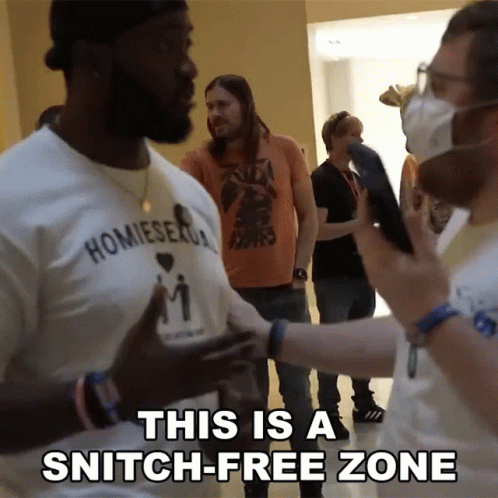 A Man Wearing A Shirt That Says ' Homiesexual ' On It Talking To Another Man GIF