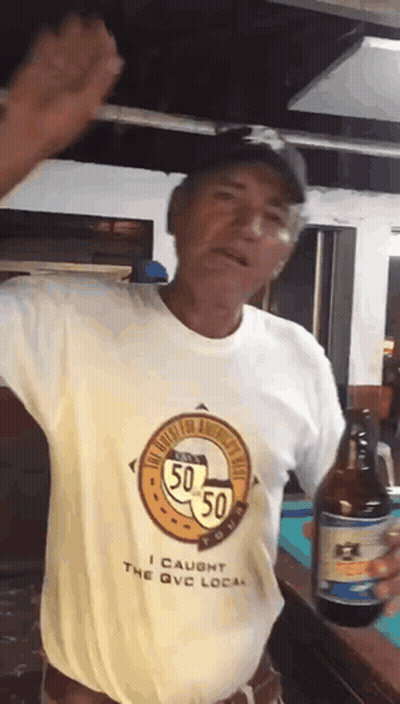 A Man Wearing A Shirt That Says I Caught The Qvc Local Is Holding A Bottle Of Beer GIF