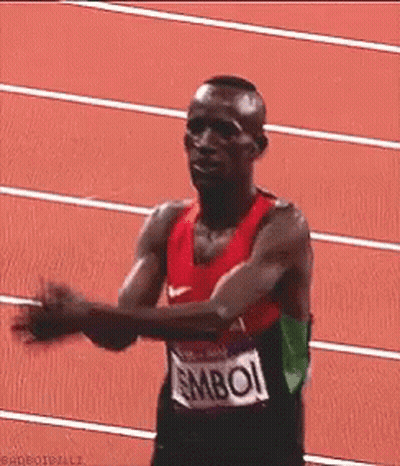 A Man Wearing A Shirt That Says ' Mboi ' On It Is Running On A Track GIF
