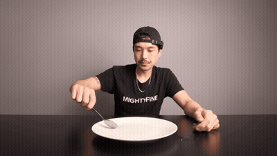 A Man Wearing A Shirt That Says Mightyfine Is Holding A Spoon Over A Plate GIF