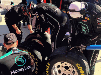 A Man Wearing A Shirt That Says Moneylion Looks At A Tire GIF