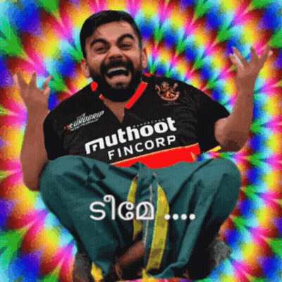 A Man Wearing A Shirt That Says Muthoot Fincorp Sits In Front Of A Colorful Background GIF