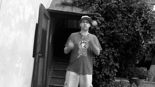 A Man Wearing A Shirt That Says New York Is Standing In Front Of A Doorway GIF