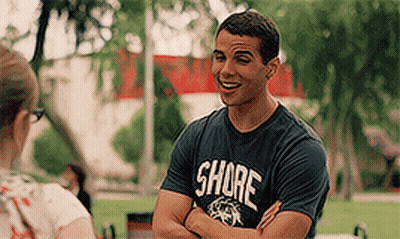 A Man Wearing A Shirt That Says Shore Is Talking To A Woman . GIF