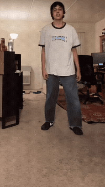 A Man Wearing A Shirt That Says Thrasher Is Standing In A Room GIF