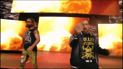 A Man Wearing A Shirt That Says Valley Club Stands Next To Another Man GIF