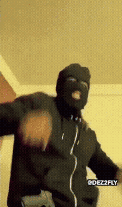 A Man Wearing A Ski Mask And Holding A Gun Is Dancing . GIF
