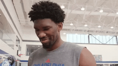 A Man Wearing A Sleeveless T-Shirt That Says Philadelphia Is Standing In A Gym . GIF