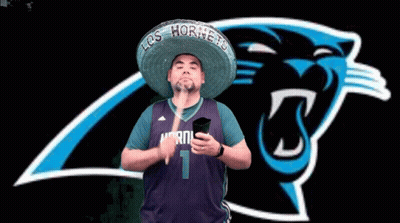 A Man Wearing A Sombrero And A Hornets Jersey Holds A Phone In Front Of A Panthers Logo GIF