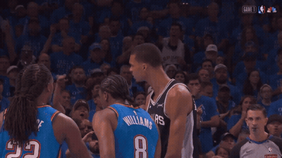 A Man Wearing A Spurs Jersey Stands In Front Of A Crowd GIF