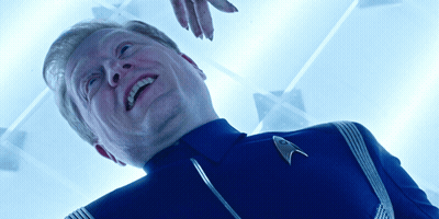 A Man Wearing A Star Trek Uniform Is Smiling And Looking Up GIF