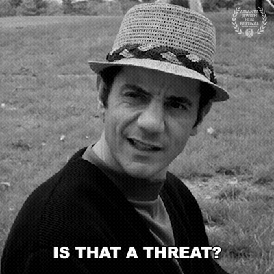 A Man Wearing A Straw Hat Says " Is That A Threat " In A Black And White Photo GIF