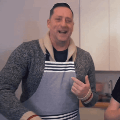 A Man Wearing A Striped Apron Is Pointing GIF