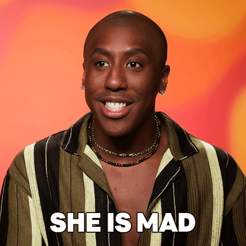 A Man Wearing A Striped Shirt And A Necklace Smiles And Says She Is Mad GIF