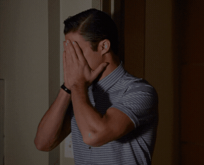 A Man Wearing A Striped Shirt Is Covering His Nose With His Hand GIF