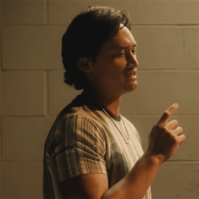 A Man Wearing A Striped Shirt Is Pointing At Something GIF