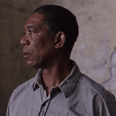 A Man Wearing A Striped Shirt Looks To His Left GIF