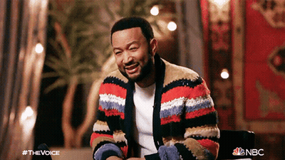 A Man Wearing A Striped Sweater Is Sitting In A Chair And Smiling GIF