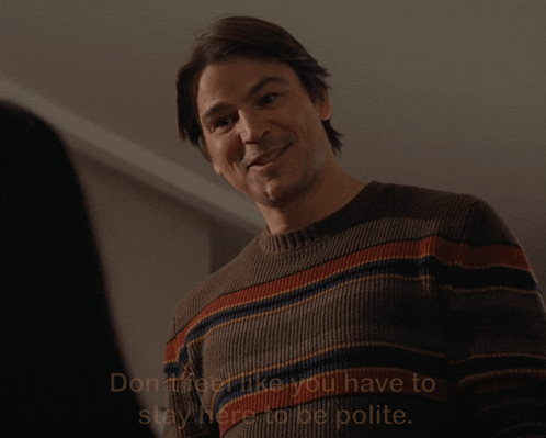 A Man Wearing A Striped Sweater Says " Don 'T Feel Like You Have To Stay Here To Be Polite " GIF