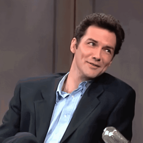 A Man Wearing A Suit And A Blue Shirt Is Sitting In Front Of A Microphone GIF