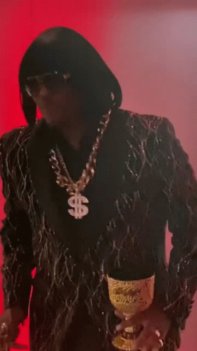 A Man Wearing A Suit And A Dollar Sign Necklace GIF