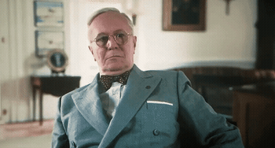 A Man Wearing A Suit And Bow Tie Looks At The Camera GIF