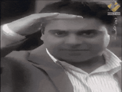 A Man Wearing A Suit And Striped Shirt Salutes With His Hand On His Forehead GIF