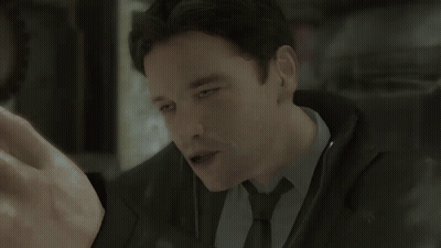 A Man Wearing A Suit And Tie Is Looking At Something GIF