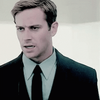A Man Wearing A Suit And Tie Is Looking At The Camera . GIF