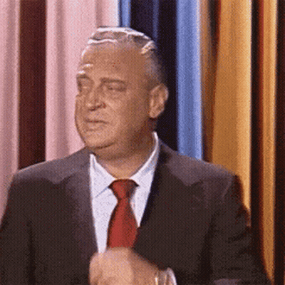 A Man Wearing A Suit And Tie Is Making A Funny Face GIF