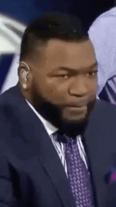 A Man Wearing A Suit And Tie Is Making A Funny Face GIF