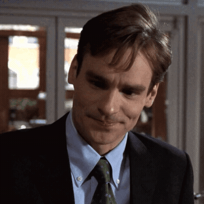 A Man Wearing A Suit And Tie Is Smiling GIF