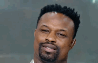A Man Wearing A Suit And Tie Is Smiling With His Eyes Closed . GIF