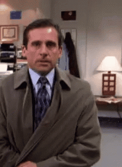 A Man Wearing A Suit And Tie Is Standing In Front Of A Lamp GIF