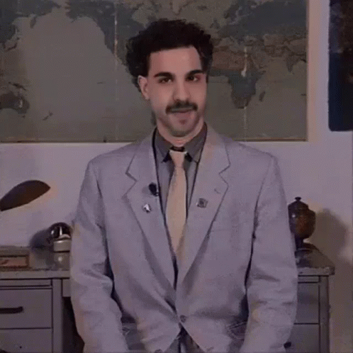 A Man Wearing A Suit And Tie Is Standing In Front Of A Map Of The World . GIF