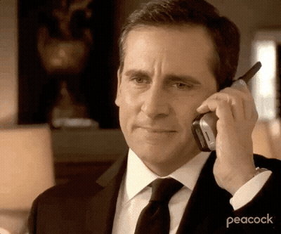 A Man Wearing A Suit And Tie Is Talking On A Cell Phone . GIF