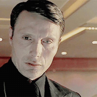 A Man Wearing A Suit And Tie Looks At The Camera GIF