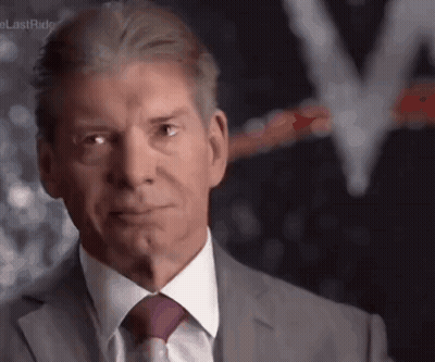A Man Wearing A Suit And Tie Looks At The Camera GIF