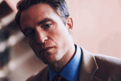 A Man Wearing A Suit And Tie Looks At The Camera GIF