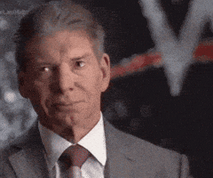 A Man Wearing A Suit And Tie Looks At The Camera GIF