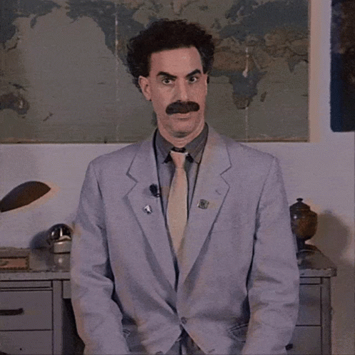 A Man Wearing A Suit And Tie With A Pin That Says ' A ' On It GIF