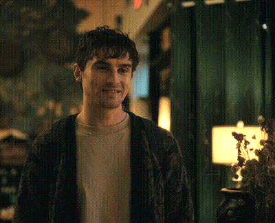 A Man Wearing A Sweater And A T-Shirt Is Smiling GIF