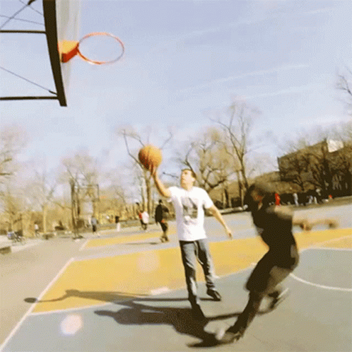 A Man Wearing A T-Shirt That Says ' Basketball ' On It Is Jumping Into A Hoop GIF