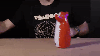 A Man Wearing A T-Shirt That Says " Sauce " Is Holding A Red And White Inflatable Animal GIF