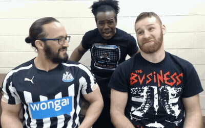 A Man Wearing A T-Shirt That Says The Business Sits Next To Two Other Men GIF
