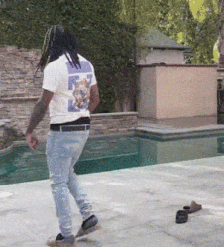 A Man Wearing A T-Shirt With A Cat On The Back Walks By A Pool GIF