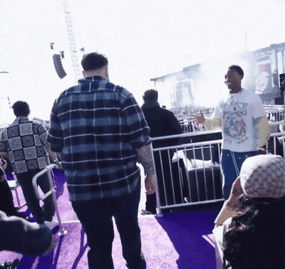 A Man Wearing A T-Shirt With A Dog On It Stands In A Crowd Of People GIF