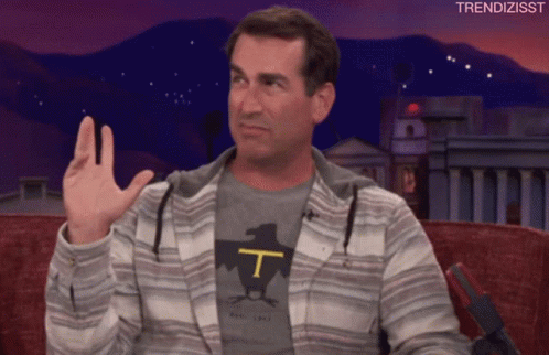 A Man Wearing A T-Shirt With The Letter T On It Waves His Hand GIF